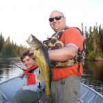 Father and son posing with a walleye fish